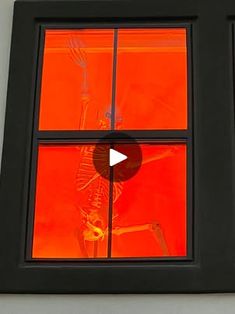 a skeleton is seen through the window of a building with red glass in front of it