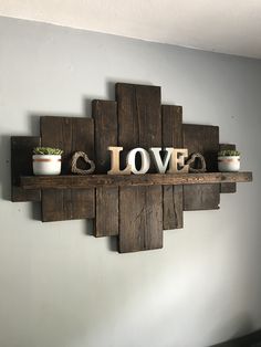 a wooden shelf with love spelled on it and two small potted plants in the middle