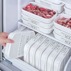 a person reaching for some meat in the refrigerator