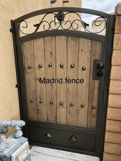 the entrance to madrid fence is made out of wood and iron, with an inscription on it