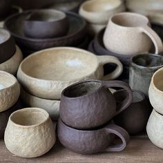 a pile of ceramic cups sitting on top of a wooden table