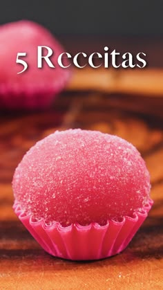 a pink cupcake sitting on top of a wooden table