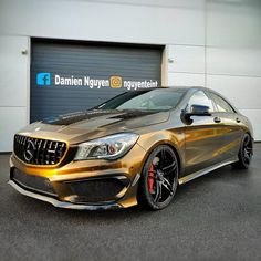 a gold mercedes cla parked in front of a garage