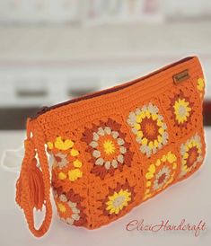 an orange crocheted purse with flowers on it