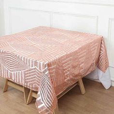 an orange table cloth with white designs on it sitting on a wooden stool in front of a wall