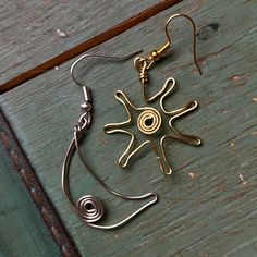 a pair of earrings sitting on top of a wooden table next to a piece of metal