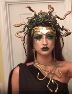 a woman with green and gold makeup is wearing a costume that has horns on her head