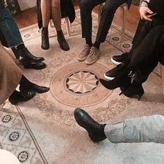 four people sitting in a circle with their feet on the floor and one person wearing black shoes