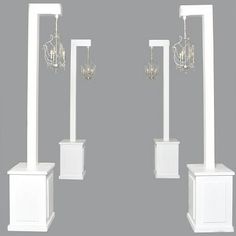 three white pedestals with chandeliers on each one and two lamps hanging from them