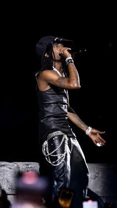 a man standing on top of a stage with his hands in the air while holding a microphone