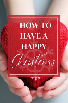 two hands holding a red christmas ornament with the words how to have a happy christmas