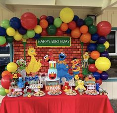 the birthday party is decorated with balloons and sesame street characters, such as elmo, cookie monster, ketchup, muppets