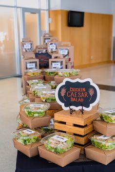 a table topped with lots of sandwiches and salads on top of wooden boxes filled with lettuce