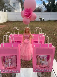 a barbie doll is standing in front of some pink bags with balloons attached to them