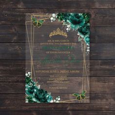 an elegant wedding card with green flowers and gold trimmings on the front, sitting on