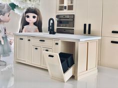 two dolls standing in front of a kitchen counter with an open dishwasher and sink