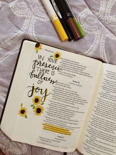 an open bible with sunflowers and pens