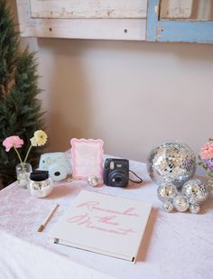 a white table topped with a mirror ball vase and other items on top of it