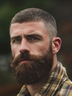 Showcasing a laid-back style, this buzzcut and beard combination is perfect for the man who carries a relaxed yet confident aura. The hair is cropped close to the head, maintaining an easy-to-care-for style, while the beard is kept thick and luxuriously full, framing the face beautifully. This look is versatile, suitable for both a weekend getaway and a casual day at the office. The natural beard texture complements the simplicity of the buzzcut, creating a balanced and approachable appearance. Men’s Hair Styles With Beard, Close Cropped Hair Men, Bald Head Style, Men’s Buzz Cut Fade, Buzz Cut Men With Beard, Short Skin Fade Haircut Men, Men Buzzcut Fade, Skin Fade Buzzcut Men, Buzz Cut And Beard