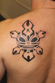 the back of a man's shoulder with an ornamental tattoo design on his chest