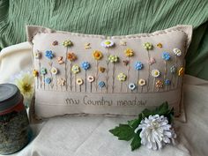 a pillow that has flowers on it and the words may country meadow written in cursive writing