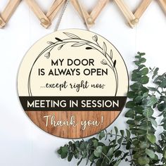 a wooden sign hanging from the side of a wall next to a potted plant