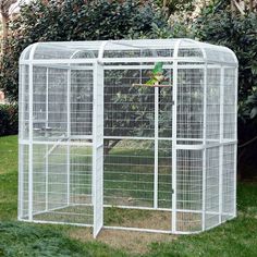 a white bird cage sitting in the grass