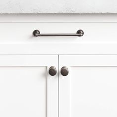 a close up view of the handles on a white cabinet with two knobs and one door handle