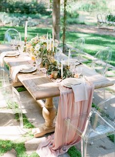 the table is set with candles, flowers and napkins for an outdoor dinner party