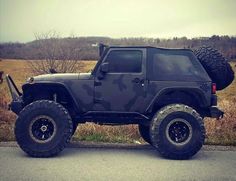 a camouflaged jeep is parked on the side of the road in front of some cows