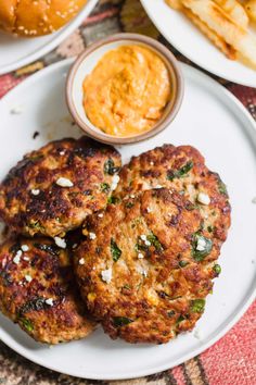 two crab cakes on a white plate next to some french fries and mustard sauces