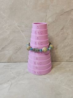 a stack of pink measuring cups sitting on top of a marble floor next to a wall