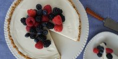 a pie with berries and blueberries on top is sitting on a plate next to a knife