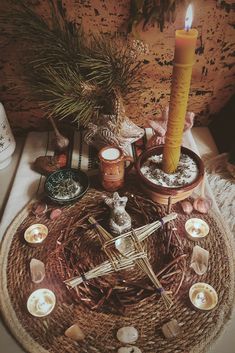 a wicker table topped with candles next to a basket filled with rocks and plants