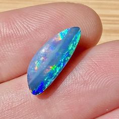 a person's hand holding an opal in their left hand