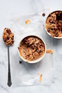 two bowls filled with ice cream sitting on top of a white counter next to a spoon