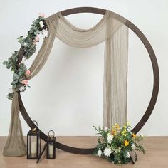 a wedding arch decorated with flowers and greenery on a wooden floor in front of a white wall