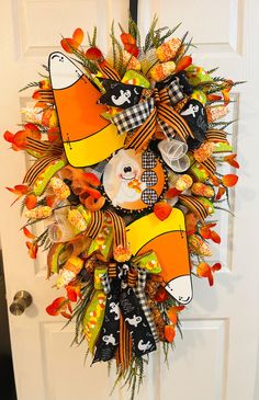 a halloween wreath on the front door decorated with orange and black shoes, pumpkins, and candy