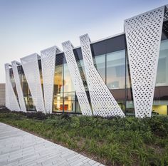 the exterior of a modern building with white perfored panels on it's sides