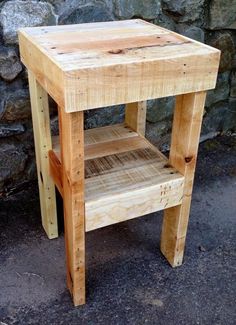 a small wooden table sitting next to a stone wall on the side of a road