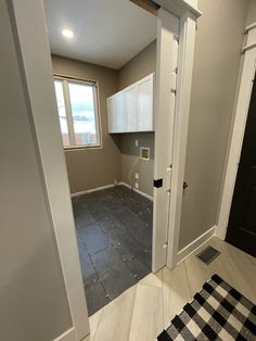 an empty room with white cabinets and black flooring is seen through the open door