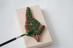 a piece of wood that has been decorated with green leaves and is sitting on a white surface