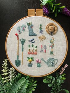 a cross stitch pattern with gardening related items on it and some plants in the background