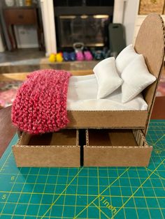 an open cardboard box with some white pillows in it and a pink blanket on top