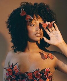 a woman with butterflies on her shoulder and hands in front of her face, posing for the camera