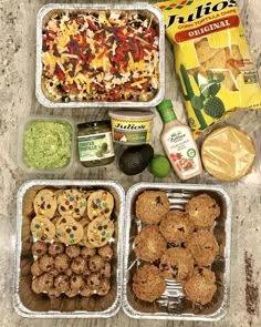 four containers filled with food sitting on top of a counter next to a bag of chips