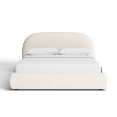 a white bed with two pillows on top of it and a night stand next to it