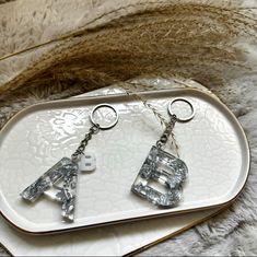 the earrings are made out of clear glass and have silver letters on each earring