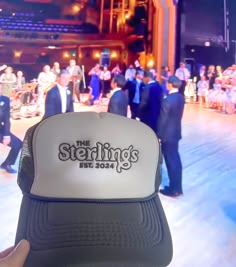 a person holding up a trucker hat in front of a stage full of people