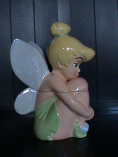 a ceramic figurine of a little fairy sitting on top of a black table